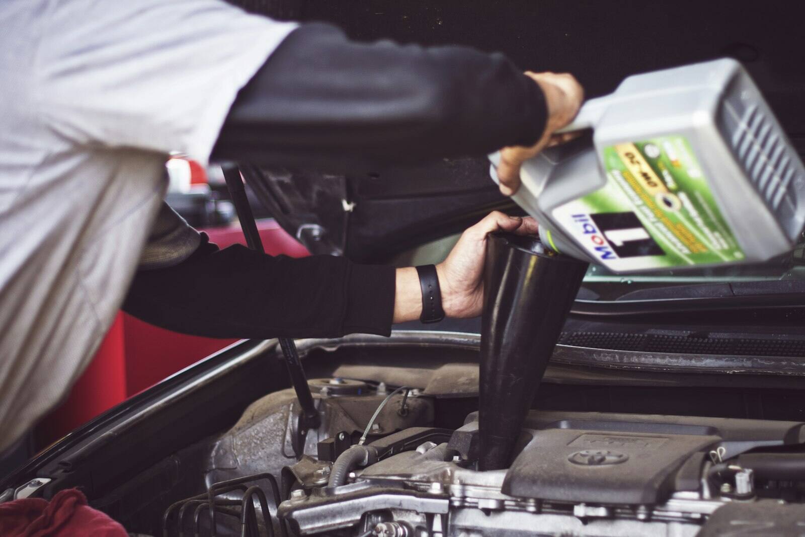 Fresh engine oil being poured during an oil change